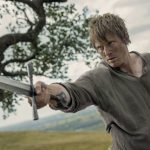 man holding sword in field looking like farmer