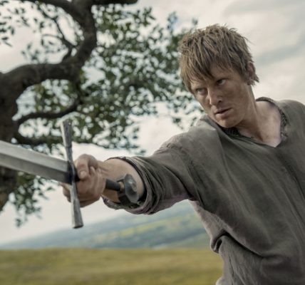 man holding sword in field looking like farmer