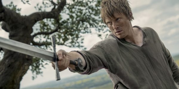 man holding sword in field looking like farmer