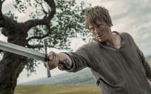 man holding sword in field looking like farmer