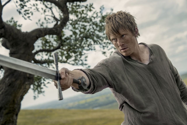 man holding sword in field looking like farmer